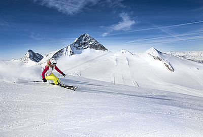 Skifahrerin allein auf Piste bei Abfahrt
